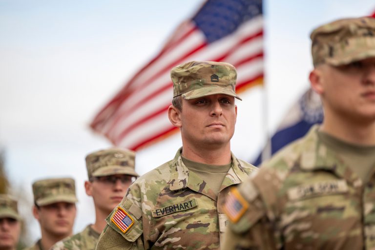Military personnel standing in front of the American Flag