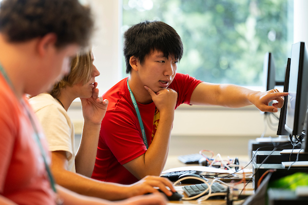 Student pointing out something on a computer screen to other students.